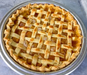 Finished peach pie with a lattice top baked to a golden brown.